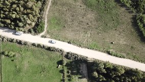 Aerial high distance top down drone video of cars driving a dirt road in Sardinia, Italy. 