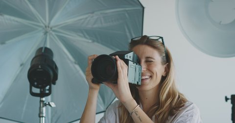 Young professional female photographer taking photos in a photo studio, creative industry jobs concept