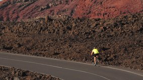 Road biking male cyclist biking on road bike cycling in amazing nature landscape. Professional cyclist athlete cycling riding bicycle training in Lanzarote, Canary Islands, Spain, Europe.