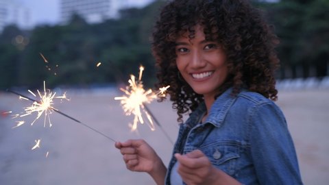 Holiday concept. A beautiful woman playing fireworks on the beach. 4k Resolution.