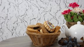 Cookies basket with kettle with coffee cup and flowers on spinning wooden table background. FHD.