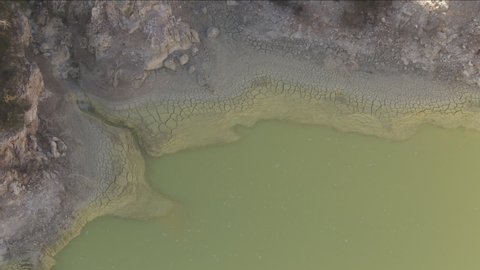 Aerial view, Rush.Medium close up and slight zoom on water filling the devils' bath, a natural pool of Wai-o-Tapu, New Zealand. Its Green color signals a strong presence of arsenic in water.