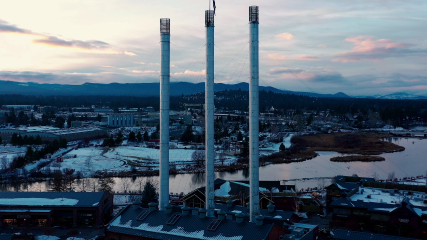 Drone flyover old chimneys at Old Mill District in Bend Oregon. Wintertime moody sunset.