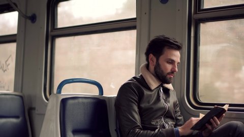 Peaceful Businessman Take Break Relax After Hard Work In Office Enjoy Reading Book On Tram.Handsome Man Sitting And Learning Book In Train Near Window. Cheerful Businessman Relaxing And Enjoying Diary