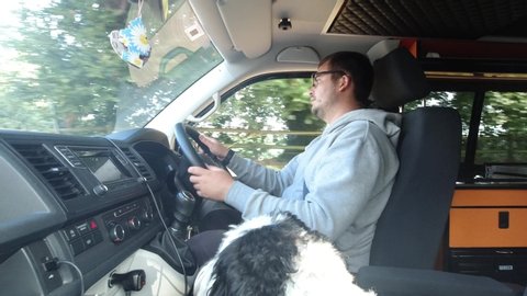 Van life man in camper van with a cute dog as passenger.