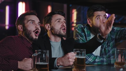 Group of guys good friends in a sport bar celebrating the victory of the match of their favorite team happy they hugging each other and feeling so excited and emotional