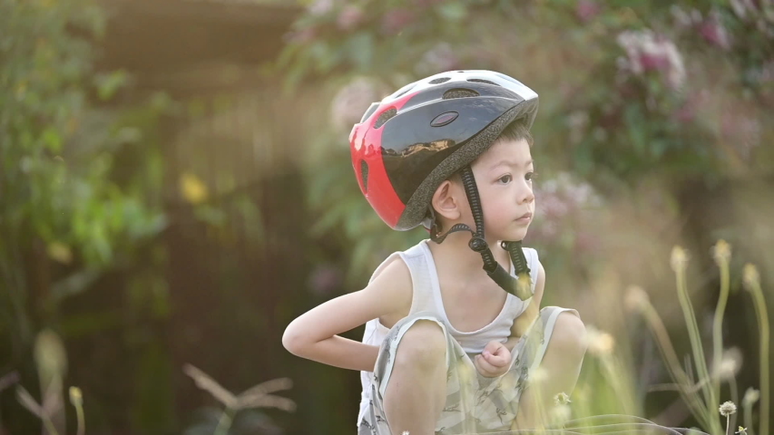 slow motion, kid smile happy wearing helmet safety for riding bicycle exercise in the morning day