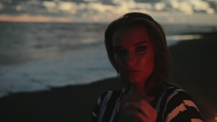 Close up portrait of young beautiful woman at sunset on the beach. Pretty girl celebrating new years eve and independence day or holiday with fireworks. City people travel. Business woman at vacation.