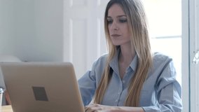 Video of concentrated young business woman working with laptop on desk in the office.