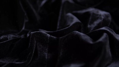 Pearl beads slowly fall onto a beautiful black velvet. Black background. 4K resolution