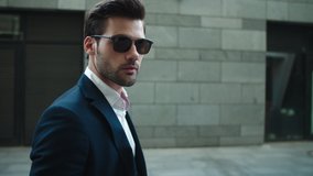 Side view serious businessman walking in suit near modern building. Confident business man wearing sunglasses at street. Portrait attractive man checking time on wrist watch outdoors. - Powered by Shutterstock - Get 15% off with code: PIKWIZARD15