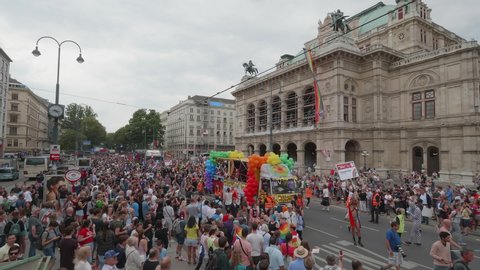 VIENNA AUSTRIA June 16 2018 – LBGT rainbow parade, gay pride parade, Regenbogenparade at the Ringstrasse Wien, wide high shot of people following a party trucks passing by the State Opera House, sound