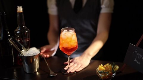 Slow motion video of mixologist making Aperol spritz cocktail, stirring the ingredients with a cocktail spoon