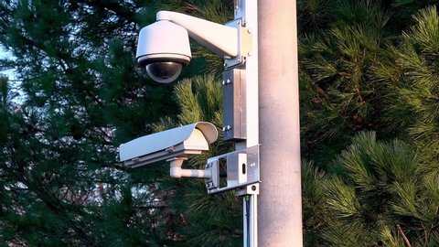 Outdoor surveillance cameras are mounted on a pole and record events from various angles.