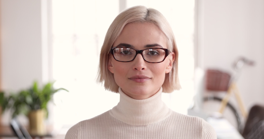 Smiling confident young adult blonde businesswoman manager professional wear glasses looking at camera in corporate office, happy smart millennial female model worker manager close up face portrait Royalty-Free Stock Footage #1046611549