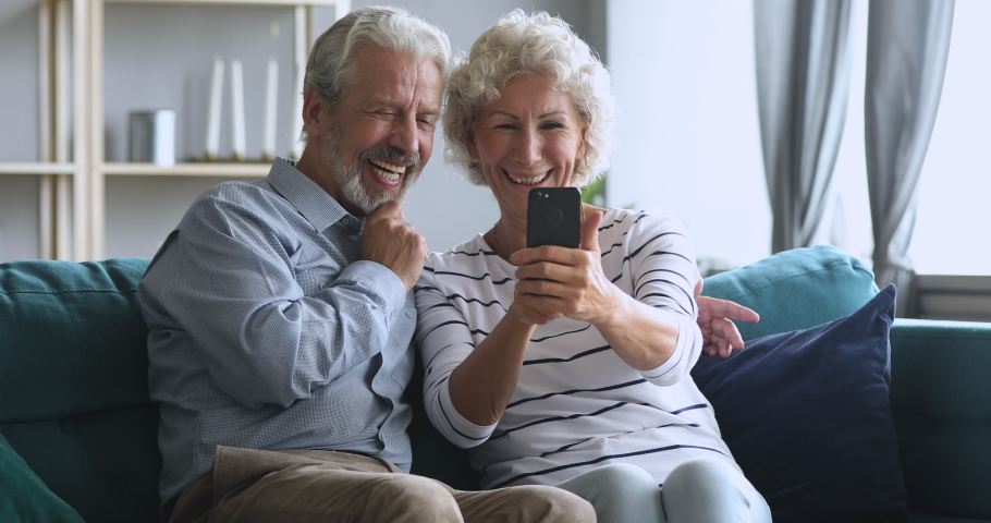 Happy middle aged family spouses having fun, making selfie photos together on smartphone at home. Laughing bonding mature older married couple using funny mobile applications or recording video. Royalty-Free Stock Footage #1046611639