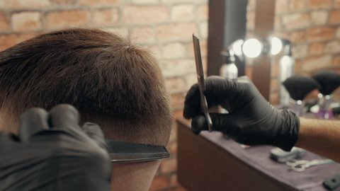 Close up hand of hair dresser using scissors and comb for hair cutting. Male hairstyling with accessories in barber shop. Hairstylist doing male hairdo in male salon