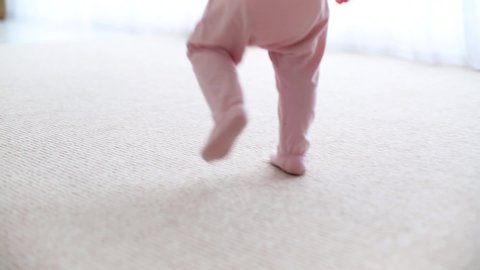 following cute little feet of baby girl walking on the carpet at home