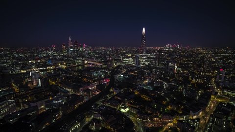 Establishing Bird Eye Aerial View Shot of London UK, London Skyline, Square Mile Panorama In foreground, Business District in the background, United Kingdom, England night evening clear sky