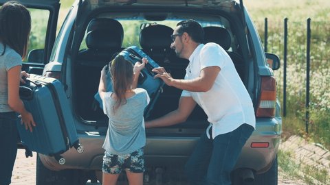 Happy family is putting suitcases into the car boot. Close up. Copy space. Hight five 4K.