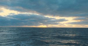 Aerial top view of peaceful calm dark blue sea water surface, cloudy sunset or sunrise sky. 4k drone video footage.