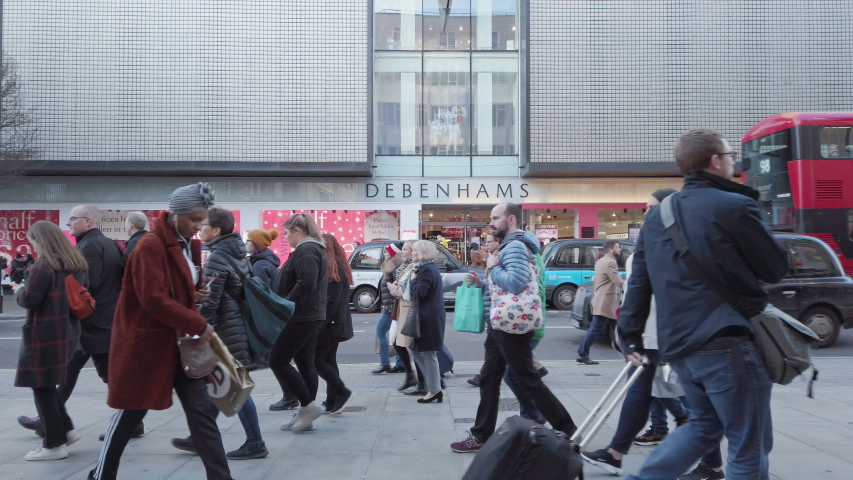 London / UK - December 30th 2019 - Crowd walking past Debenhams shop front on Oxford Street in central london, in slow motion. 