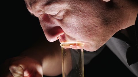 A man smokes marijuana through a Bong.Draws smoke from a glass Bong.Close-up.The legalization of cannabis in the world and in USA.Smoking medical marijuana closeup.On the black background of the face.