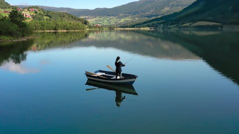 Woman on the boat catches a fish on spinning in Norway. Fishing in Norway is a way to embrace the local lifestyle. Countless lakes and rivers and an extensive coastline means outstanding opportunities