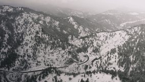 Flying over snow covered mountain in a snow storm. Drone aerial view outside Boulder, Colorado. 4k view of the forest, clouds and trees above the Rocky Mountains