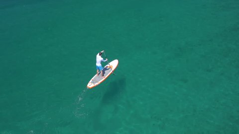 Aerial - Vertical, side view of a young man SUP paddling Stock-video