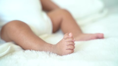 Closeup tiny newborn baby toes feet on white coverlet blanket