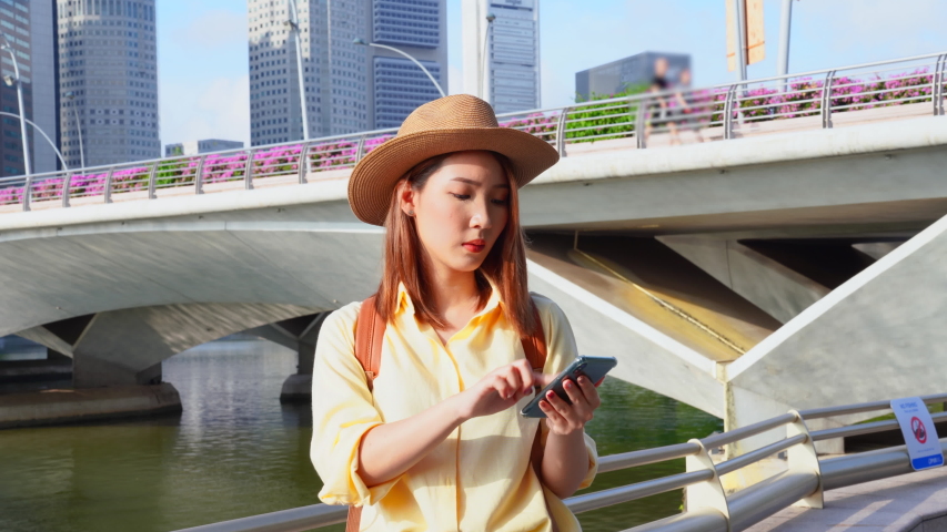 Asian female talking with cellphone while traveling in the Singapore city