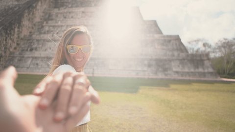 Follow me to concept, couple holding hands at Chichen Itza in Mexico. People travel concept, man's personal perspective of following girlfriend. woman leading man. 