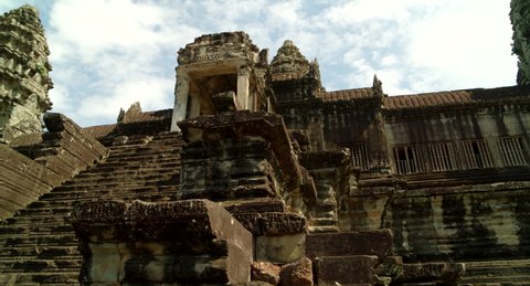 Tracking shot through Angkor Wat temple courtyard revealing towers.