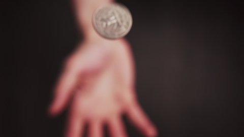 Slowmotion shot tossing a coin to flip on heads or tails quarter USD and catch it very fast