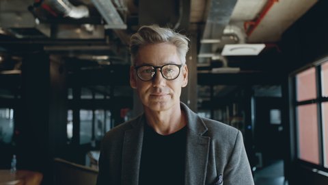 Confident mature businessman working in a modern office. Happy mature businessman wearing spectacles and looking at camera