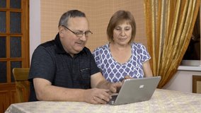 A man and a woman communicate with friends via video communication through a laptop. An old man and an old woman communicate and wave their hands while looking into a laptop. The family is sitting in