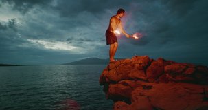 Extreme cliff jumping man backflipping off of an sea cliff with burning red hot flares, epic stuntman moments, people are awesome