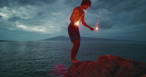 Extreme sports stunt man backflipping off of a sea cliff into the ocean with burning hot red flares, radical cliff jumping athlete, people being awesome