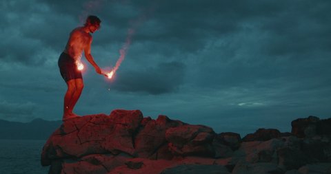 Extreme sports stunt man backflipping off of a sea cliff into the ocean with burning hot red flares, radical stuntman moments, people being awesome