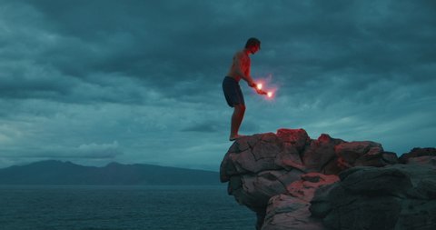 Extreme sports cliff diver doing a backflip off of a sea cliff with burning red flares, epic video of people being awesome, backflips with fireworks