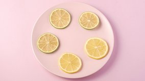 Fresh tasty lemon and lime slices rotating on pink plate, stop motion animation 4k video with citrus fruits on minimal background, top view
