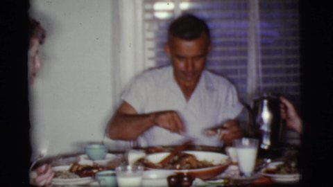 COTTONWOOD ARIZONA-1968: Man Wearing White Shirt Eats Dinner With Family At Table Covered With Lace Tablecloth