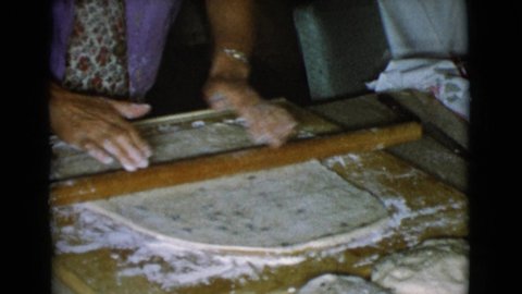COTTONWOOD ARIZONA-1968: Woman Wearing Purple Shirt Rolls Out Dough With Brown Rolling Pin