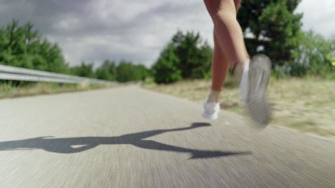 Tracking shot of woman jogging outdoors on sunny day