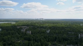 Aerial view of abandoned buildings, lake and streets overgrown with trees in city Pripyat near Chernobyl nuclear power plant. Exclusion Zone. Camera pans right. 4K drone footage.