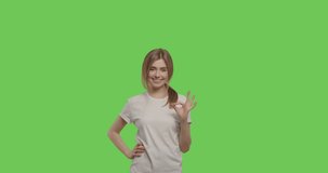 Young cheerful caucasian woman showing ok sign over green screen background Chroma Key. 4k video footage slow motion 60 fps