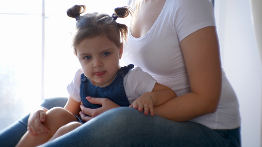 mother and daughter in white t-shirts sitting on the window in the Studio with a photographer