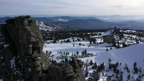 Hiker man standing on the edge of  cliff, winter mountains landscape, drone aerial video