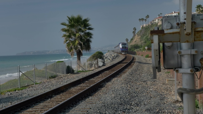 Railroad at California coast train moving between palms next to ocean pacific surfliner in San Clemente
